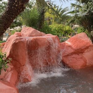 Photo Yes, pool builders can create pool designs that accommodate water features like waterfalls or grottos